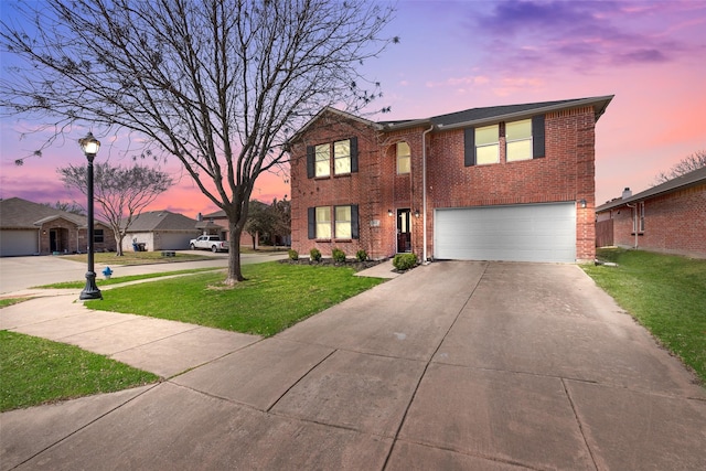 traditional home featuring a yard, brick siding, concrete driveway, and an attached garage