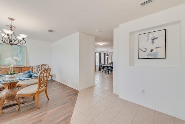 dining space with light tile patterned floors, visible vents, baseboards, and a chandelier