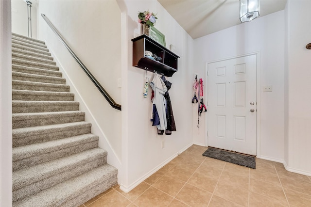 foyer featuring light tile patterned floors, stairway, and baseboards