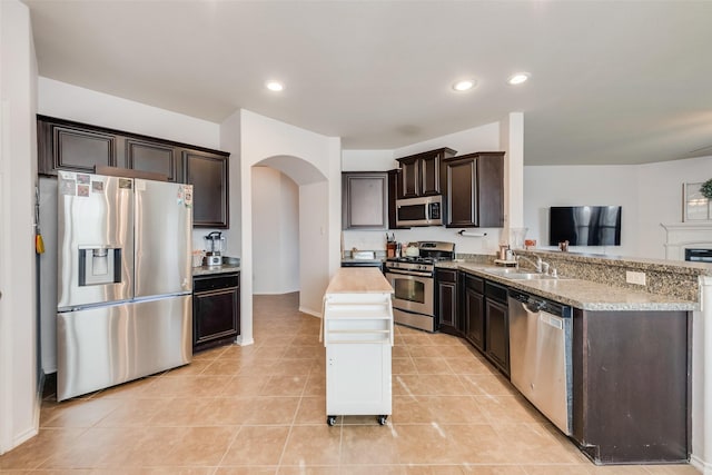 kitchen with recessed lighting, arched walkways, dark brown cabinets, and appliances with stainless steel finishes