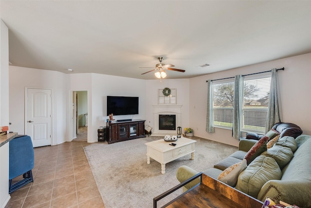 living room featuring visible vents, light tile patterned floors, a ceiling fan, and a glass covered fireplace