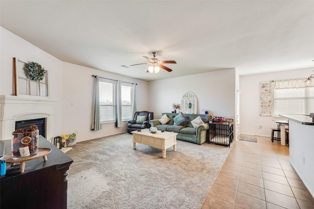 living area with ceiling fan, a fireplace, baseboards, visible vents, and light tile patterned flooring