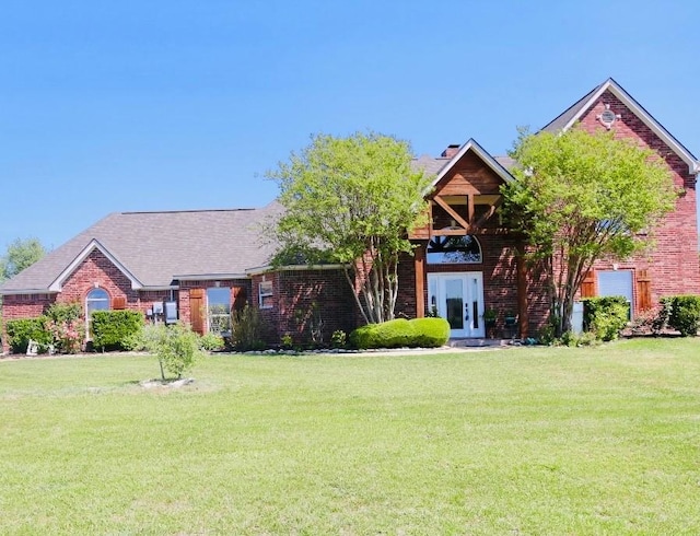 view of front facade featuring a chimney, a front yard, and brick siding