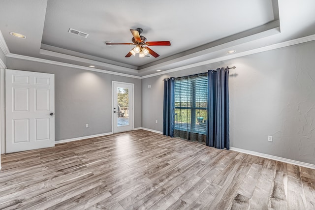 spare room with visible vents, a tray ceiling, wood finished floors, and ceiling fan