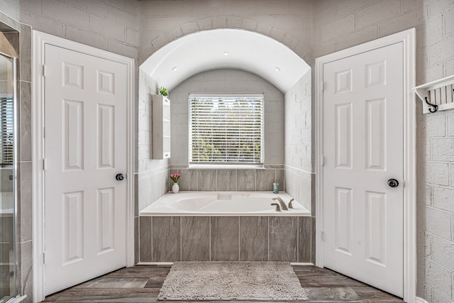 bathroom with a garden tub and wood finished floors