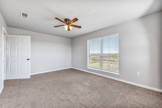 empty room with carpet flooring, a ceiling fan, and visible vents
