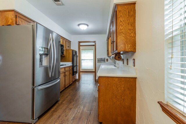 2881 Selma Ln, Farmers Branch, TX 75234 - kitchen with black appliances, brown cabinets, a textured ceiling, dark wood-style floors, and light countertops