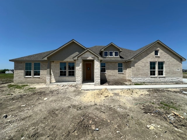 property under construction with a shingled roof and stone siding