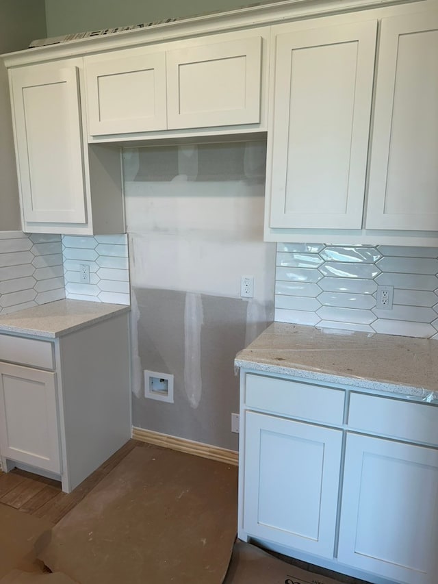 kitchen featuring white cabinets, backsplash, and light stone counters