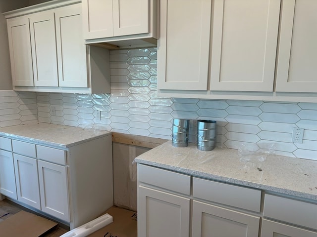 kitchen featuring tasteful backsplash, white cabinetry, and light stone counters