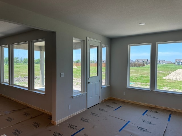doorway with plenty of natural light, baseboards, and a textured ceiling