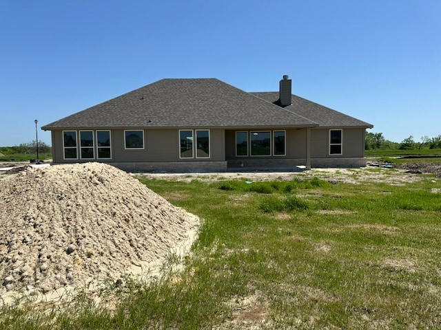 rear view of house with a chimney and a shingled roof