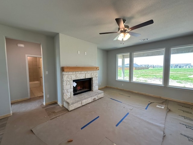 unfurnished living room featuring visible vents, a stone fireplace, baseboards, and ceiling fan