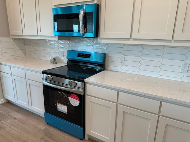 2465 Blackjack Oak Rd, Oak Ridge, TX 75161 - kitchen with appliances with stainless steel finishes, light wood-style flooring, white cabinets, and light stone counters