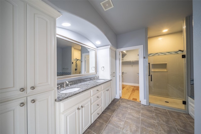 bathroom featuring a sink, visible vents, a walk in closet, and a stall shower