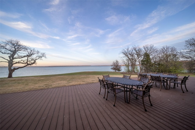 wooden terrace featuring outdoor dining space, a lawn, and a water view