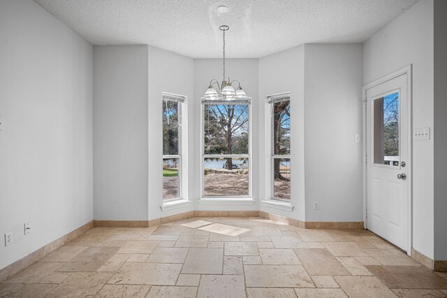 5327 Dusty Rd, Athens, TX 75752 - unfurnished dining area featuring a textured ceiling, a chandelier, stone tile floors, and baseboards