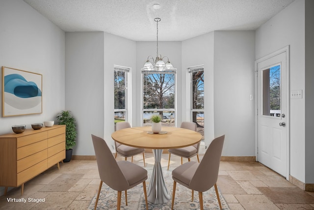 5327 Dusty Rd, Athens, TX 75752 - dining area featuring stone tile flooring, a textured ceiling, a chandelier, and baseboards