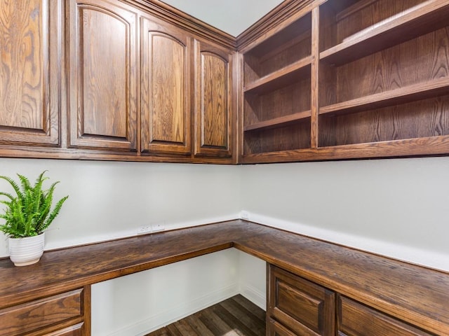 unfurnished office featuring built in study area, baseboards, and dark wood-style flooring