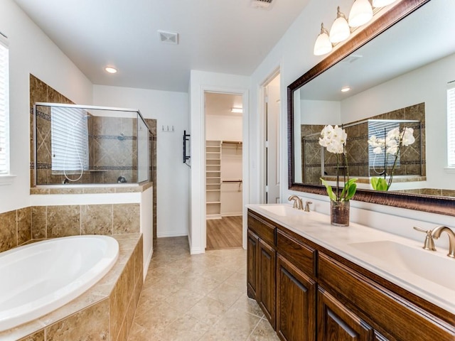 bathroom featuring a garden tub, a sink, a stall shower, a spacious closet, and visible vents