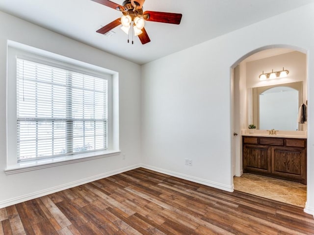spare room with wood finished floors, a healthy amount of sunlight, and ceiling fan