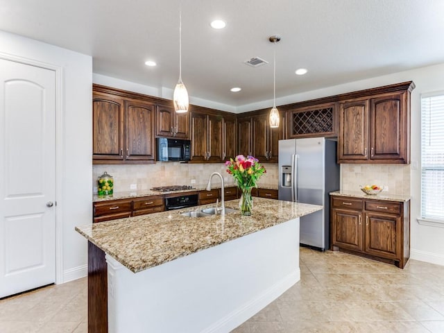kitchen with light stone counters, backsplash, a sink, pendant lighting, and appliances with stainless steel finishes