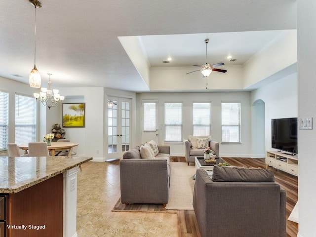 living area with baseboards, crown molding, french doors, and ceiling fan with notable chandelier