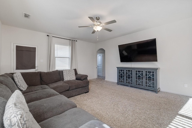 carpeted living area featuring arched walkways, ceiling fan, visible vents, and baseboards
