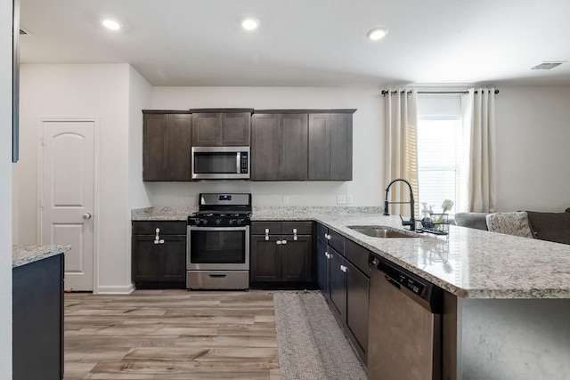 kitchen with visible vents, dark brown cabinets, light wood-type flooring, a sink, and stainless steel appliances