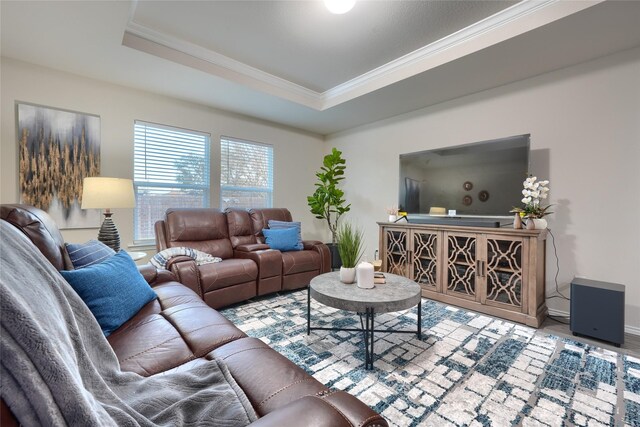 living room with a tray ceiling, wood finished floors, baseboards, and ornamental molding