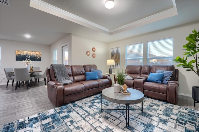 living room featuring visible vents, crown molding, a tray ceiling, and wood finished floors