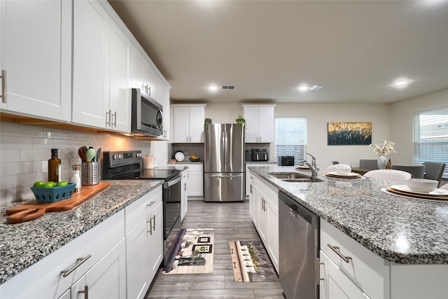 kitchen with a sink, tasteful backsplash, white cabinetry, stainless steel appliances, and dark wood-style flooring