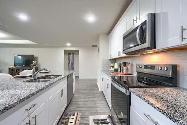 kitchen featuring backsplash, recessed lighting, appliances with stainless steel finishes, white cabinetry, and a sink