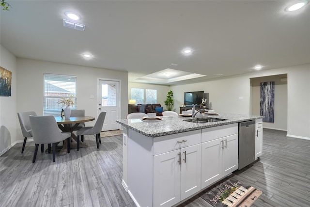 kitchen featuring a center island with sink, visible vents, light wood finished floors, a sink, and dishwasher