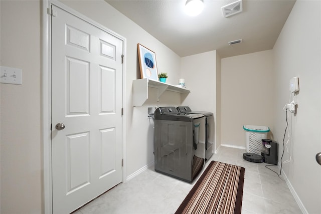 washroom featuring light tile patterned floors, laundry area, washing machine and dryer, and visible vents