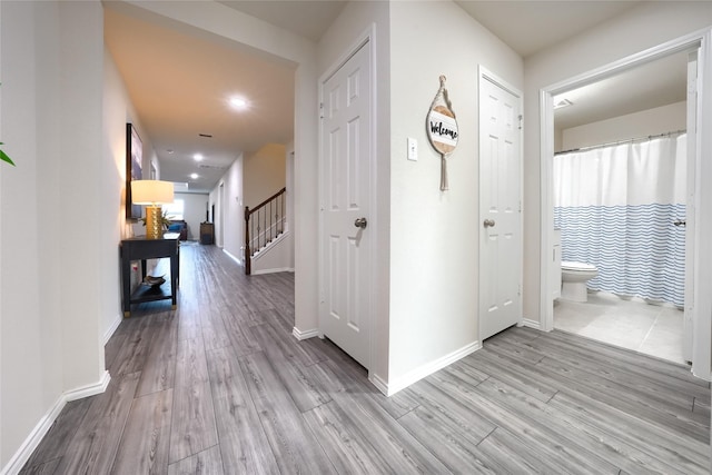 corridor featuring stairway, recessed lighting, wood finished floors, and baseboards