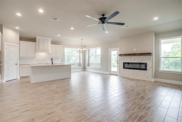 312 Falcon Ct, Springtown, TX 76082 - unfurnished living room with baseboards, a ceiling fan, a glass covered fireplace, recessed lighting, and a chandelier