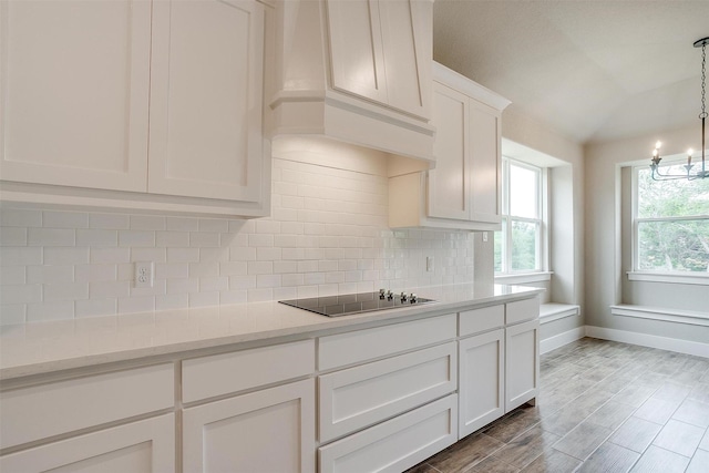 312 Falcon Ct, Springtown, TX 76082 - kitchen with black electric stovetop, backsplash, premium range hood, a chandelier, and white cabinetry