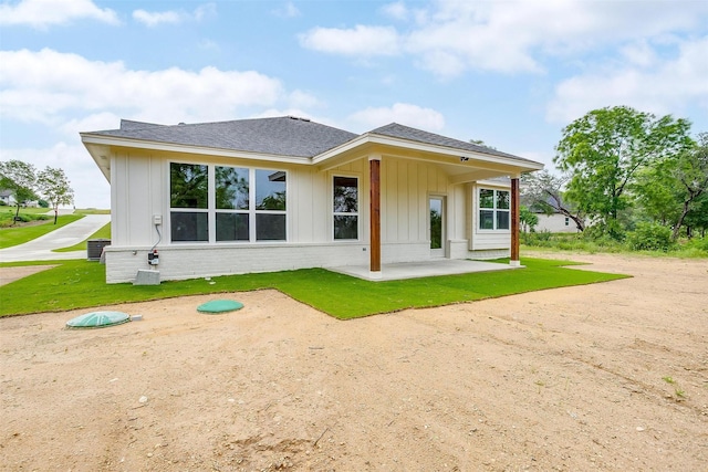 312 Falcon Ct, Springtown, TX 76082 - back of house featuring board and batten siding, a patio, a shingled roof, a yard, and brick siding