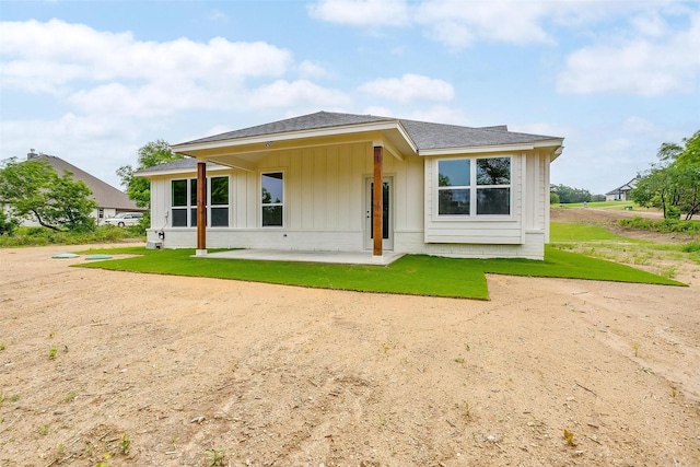 312 Falcon Ct, Springtown, TX 76082 - rear view of house with board and batten siding, a patio area, a lawn, and roof with shingles