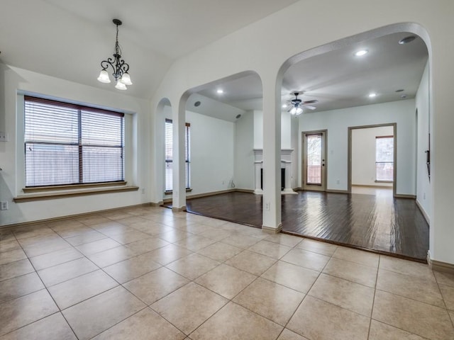4406 Winding Glen Ln, Mansfield, TX 76063 - unfurnished living room featuring light tile patterned floors, a ceiling fan, arched walkways, a fireplace, and baseboards