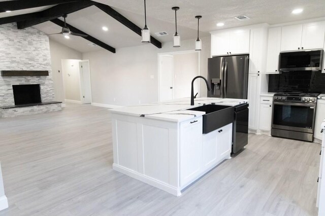 kitchen with vaulted ceiling with beams, ceiling fan, light wood-style floors, appliances with stainless steel finishes, and white cabinetry