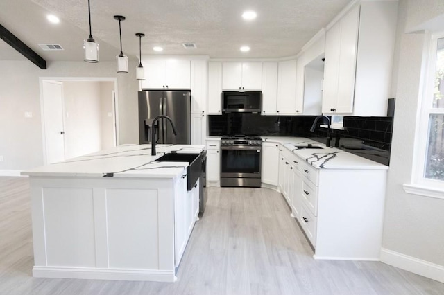 kitchen with a sink, tasteful backsplash, white cabinetry, and stainless steel appliances