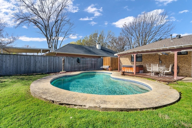 view of pool featuring a lawn, a wooden deck, a hot tub, a fenced in pool, and a fenced backyard