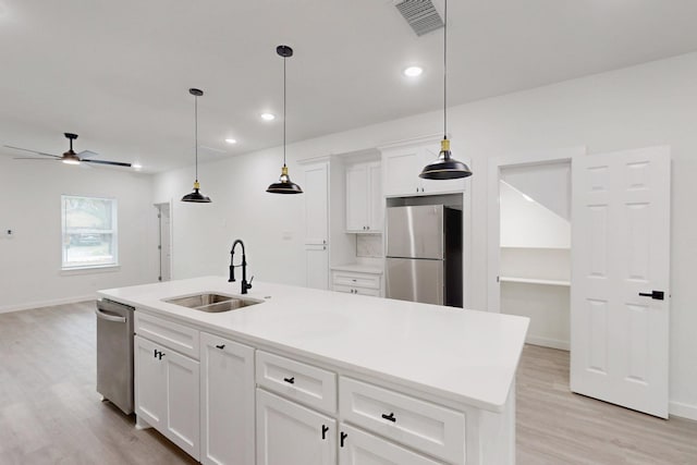 kitchen featuring light wood finished floors, a sink, visible vents, and freestanding refrigerator