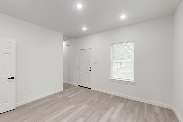 spare room featuring light wood finished floors, baseboards, and recessed lighting