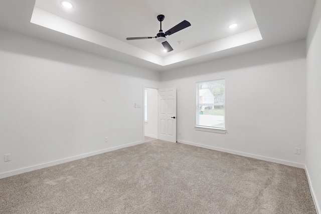 carpeted empty room with recessed lighting, a raised ceiling, baseboards, and ceiling fan