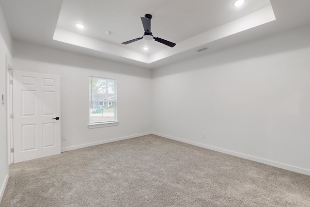 carpeted empty room with recessed lighting, a tray ceiling, visible vents, baseboards, and ceiling fan