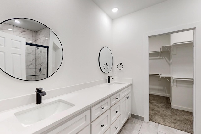 full bath with a walk in closet, double vanity, a shower stall, and a sink