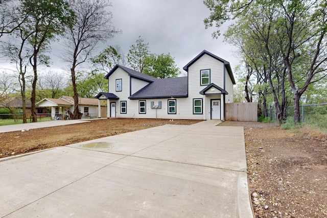 modern inspired farmhouse with fence, driveway, and a shingled roof
